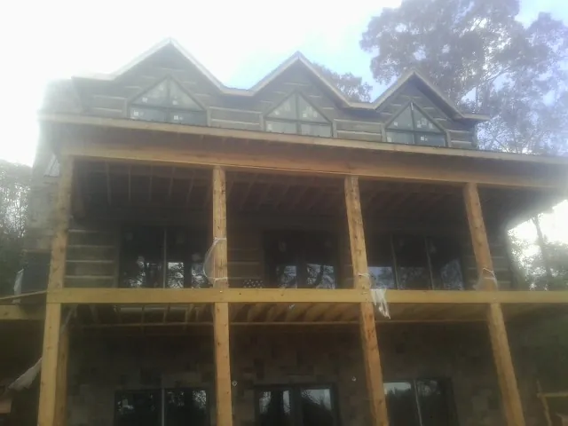 Dormers and porch framing on a large log home under construction — Roof Coating work by our crew in Mundelein