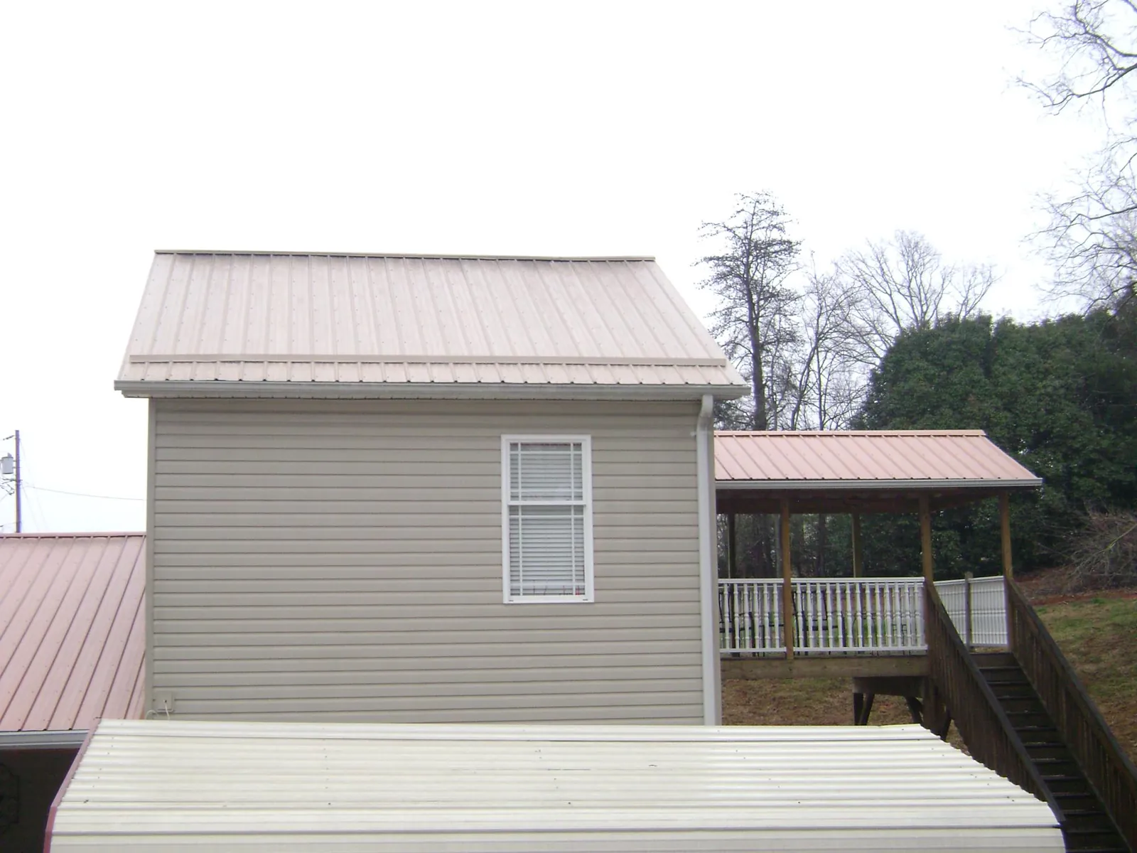 Tan metal roofs on a two story addition and attached porch, from a Roof Replacement job in Mundelein