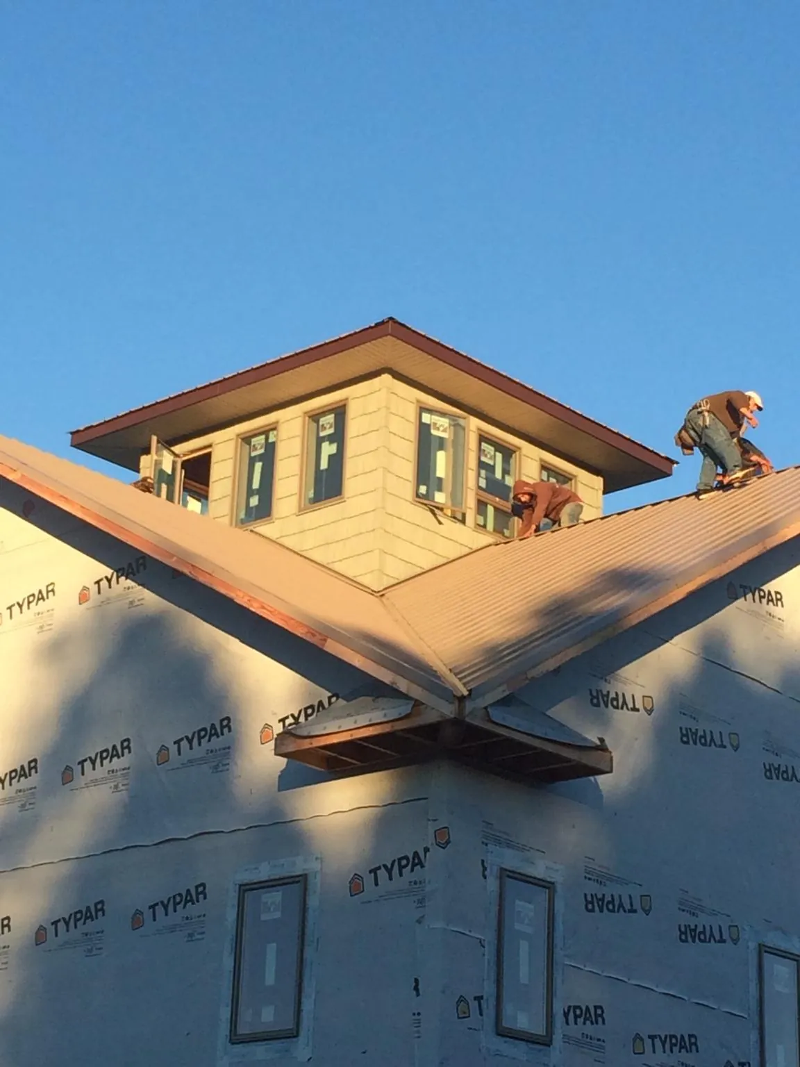 Roofers working around a rooftop cupola on a new metal roof at sunset — Roof Waterproofing in Mundelein by Roofing Brothers